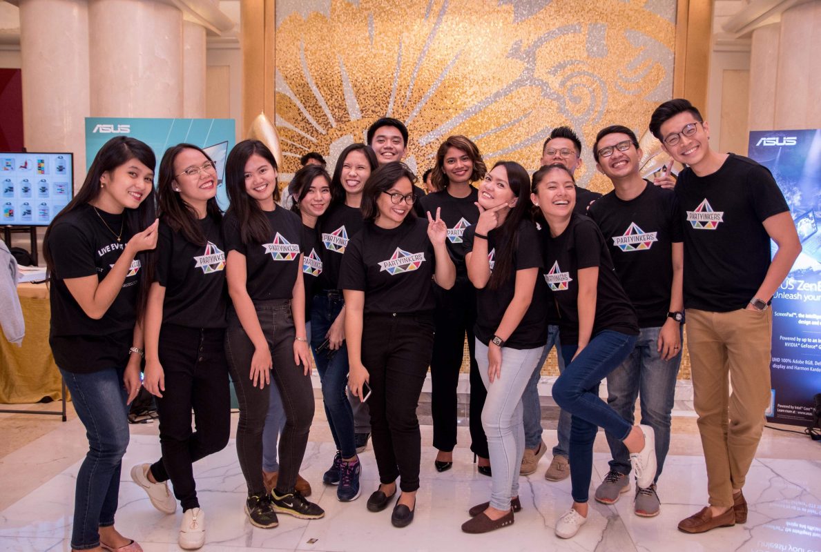 The Partyinkers team posing together at an event, all wearing branded t-shirts with the company logo. The smiling team members are ready to help make your next Dinner and Dance event stand out with their personalized services and live printing experiences.