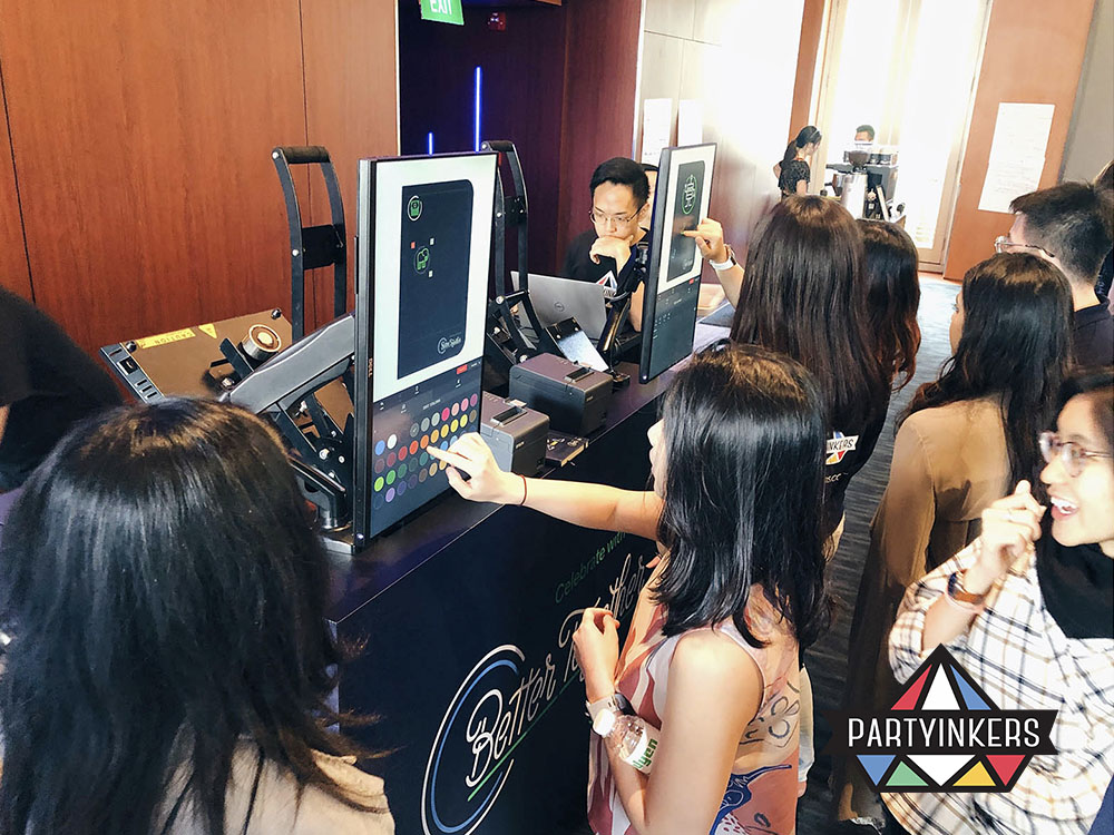 Attendees interact with digital screens to customize products at an event, showcasing personalized experiences through live digital printing services.