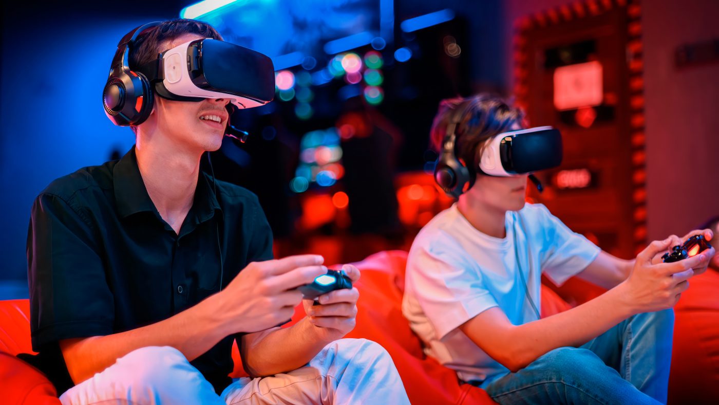 Two participants immersed in a virtual reality experience, playing tech-savvy games at a Dinner and Dance event. They are seated with VR headsets and controllers, showcasing the integration of technology into engaging and innovative activities for corporate events.