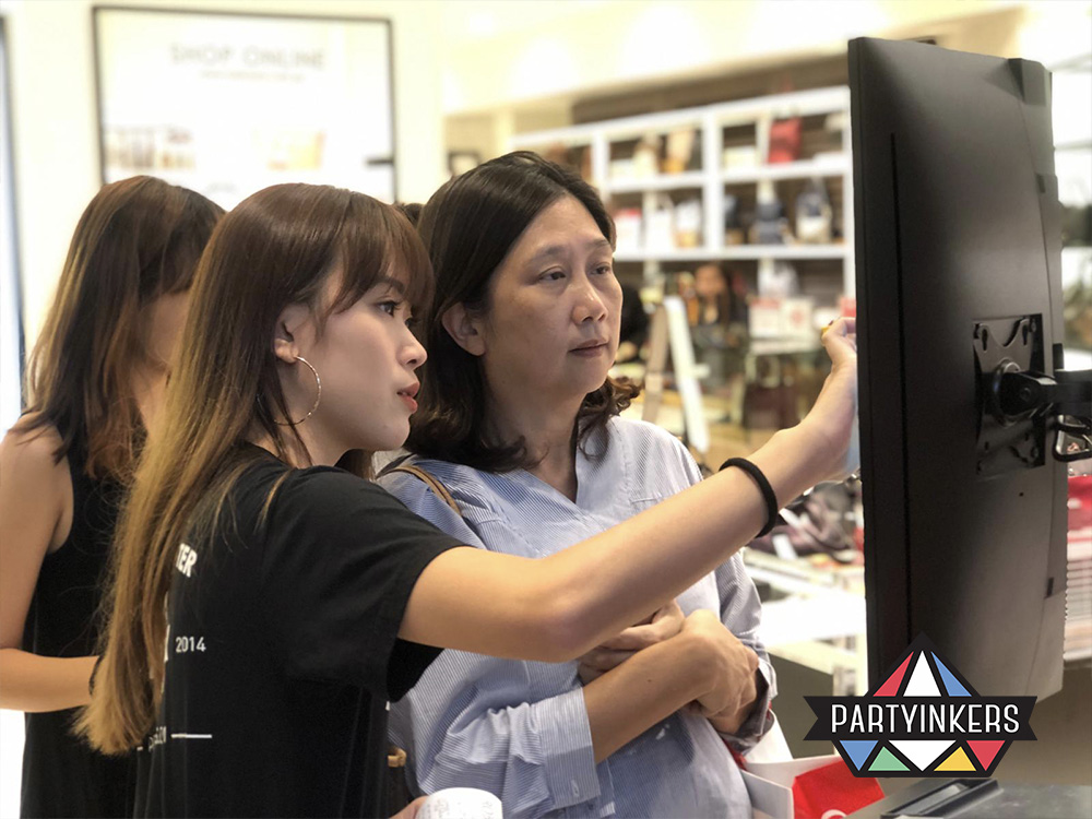 An attendee at a Robinsons event using a touchscreen to customize eco-friendly products, showcasing Partyinkers' live printing service for sustainable and personalized conference gifts for attendees.