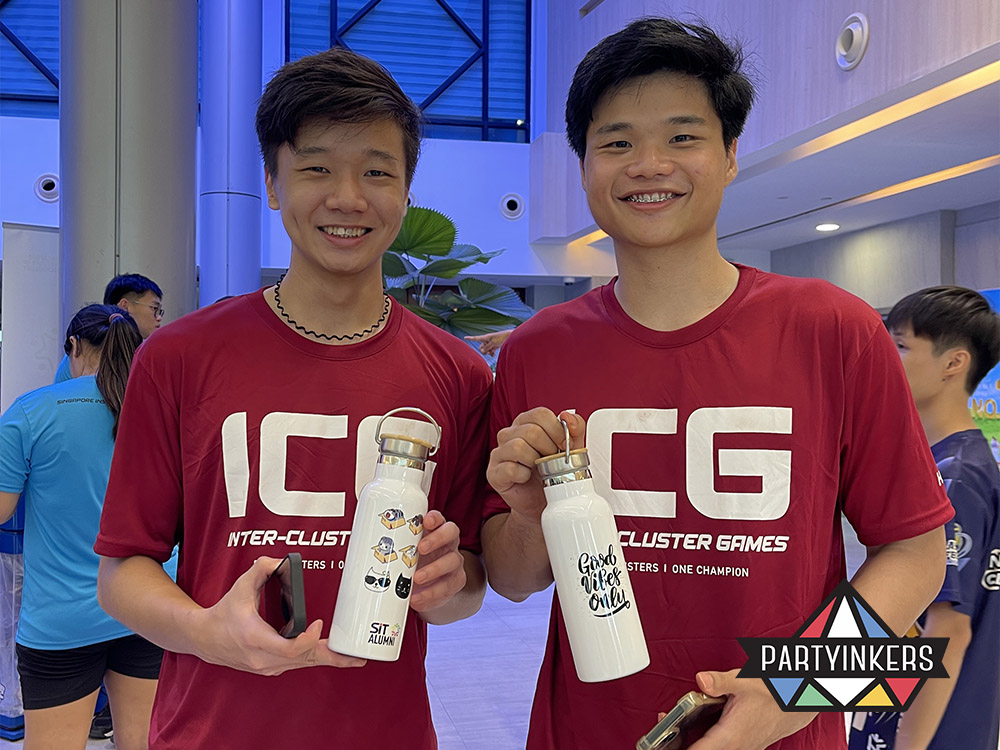 Two participants at the SIT ICG event proudly displaying their personalized bamboo lid thermo flasks with custom designs as conference gifts for attendees, created using Partyinkers' live laser engraving service.