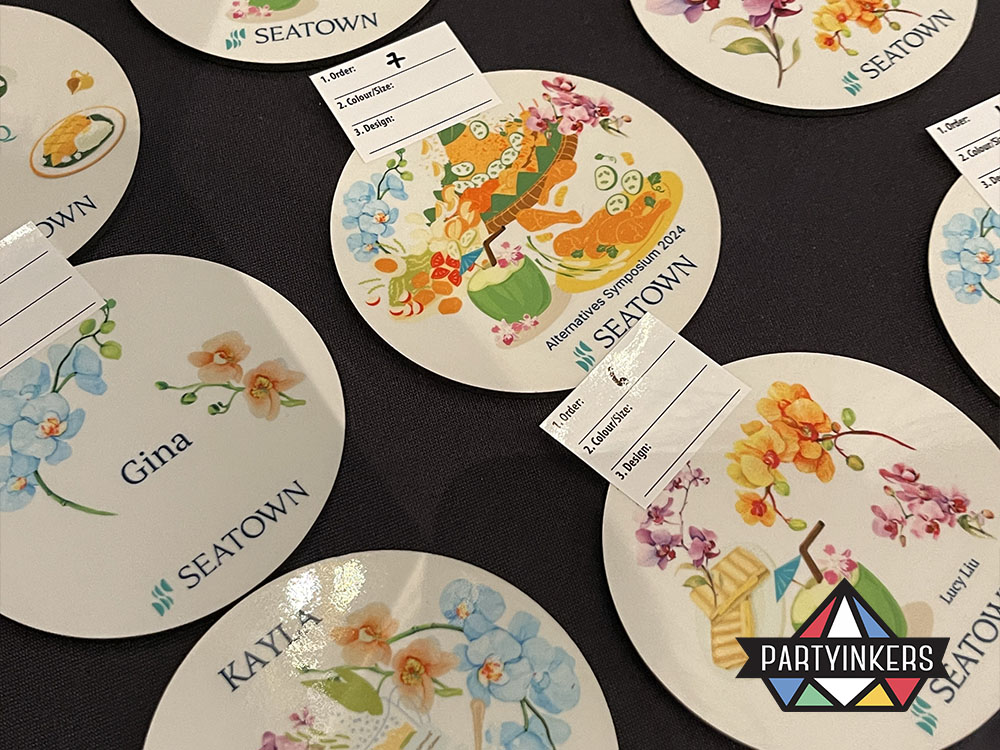 A collection of beautifully designed personalized coasters from the Seatown event, featuring attendee names and vibrant custom artwork, created using Partyinkers' live printing service.