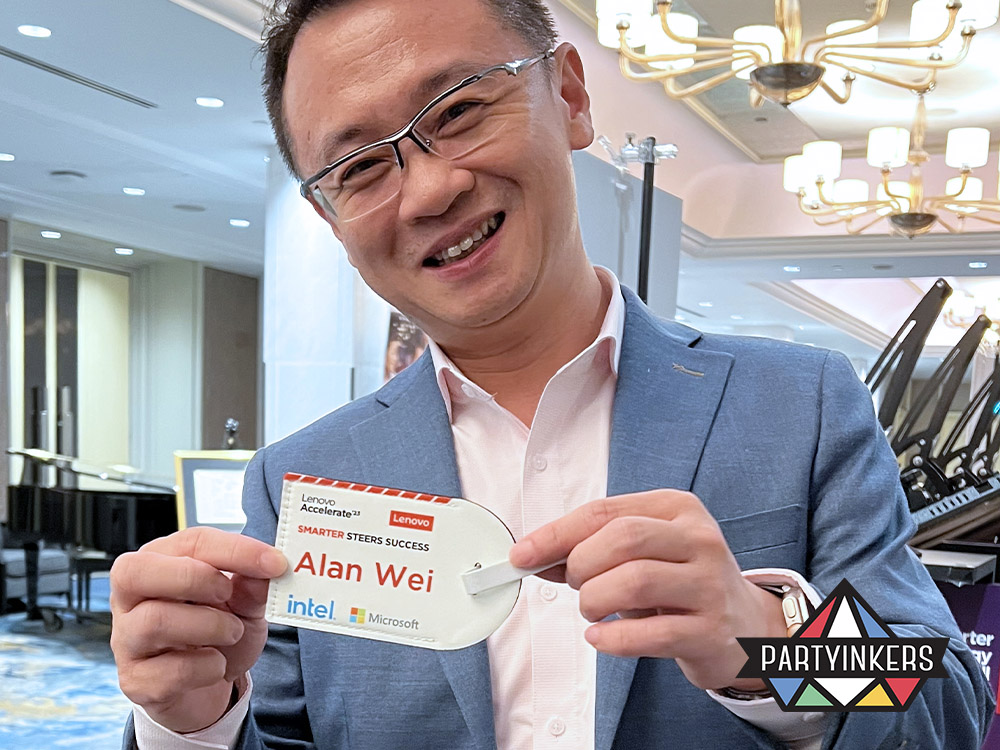 A smiling attendee proudly holding up a personalized event-specific luggage tag from a corporate conference, created using Partyinkers' live printing service.