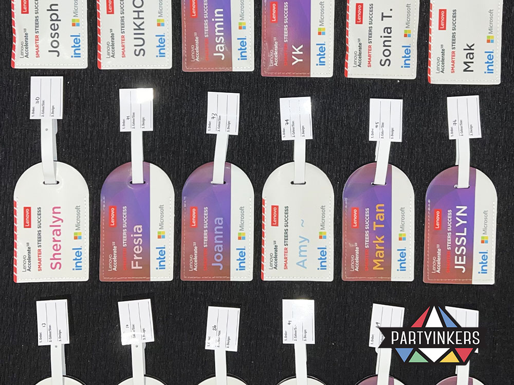 A collection of personalized event-specific luggage tags as conference gift for attendees displayed at a conference, featuring attendee names and event branding, created using Partyinkers' live printing service.