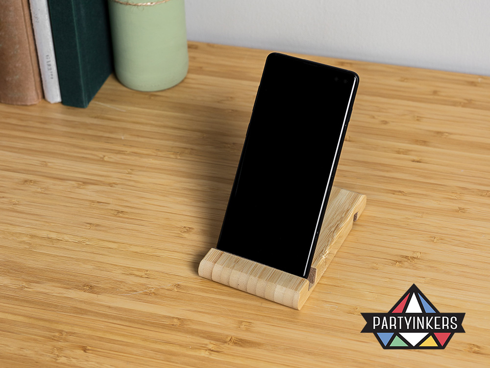 A sleek wooden portable phone stand holding a smartphone on a desk, showcasing a practical and customizable conference swag item provided by Partyinkers.
