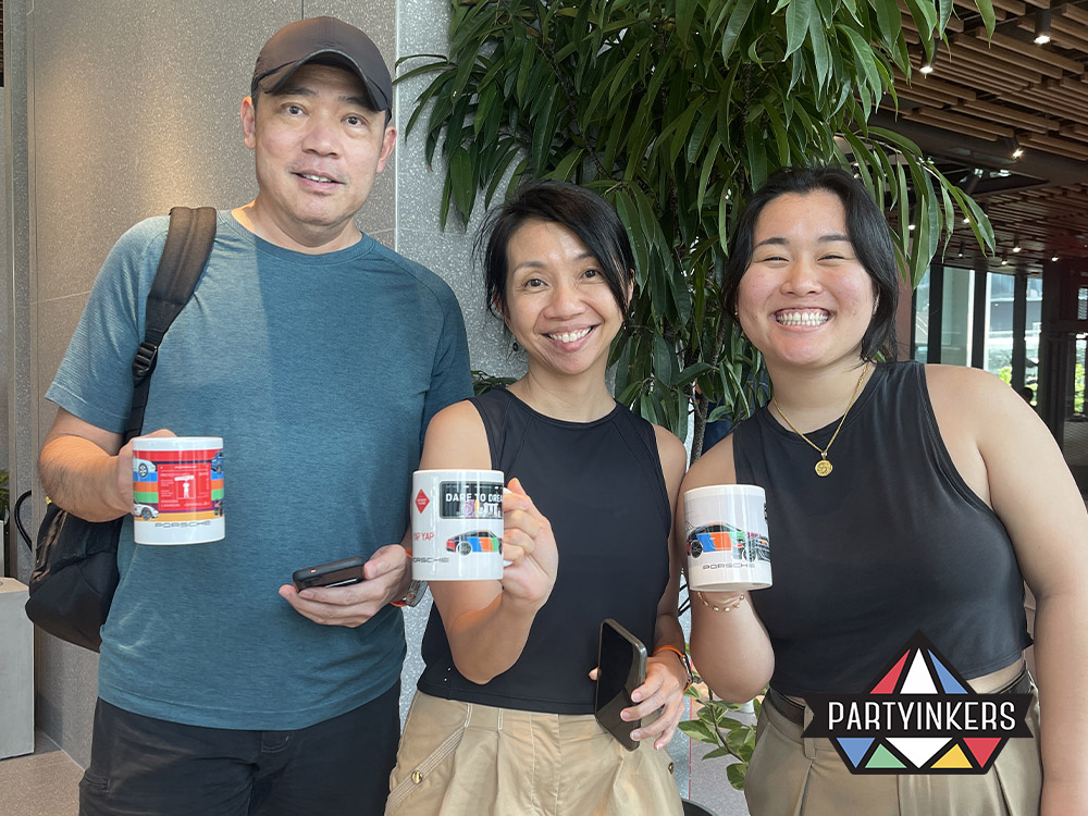 Three attendees proudly displaying their personalized mugs with custom designs, created using Partyinkers' live printing service at a corporate event.