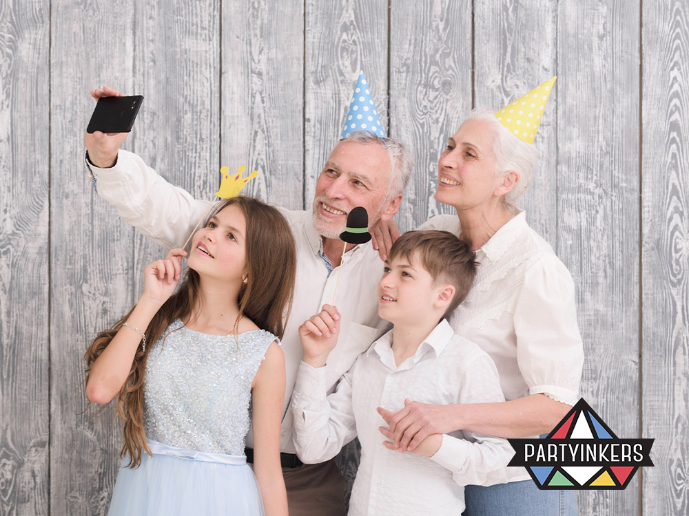 Families posing at a themed photo booth, smiling and holding fun props.