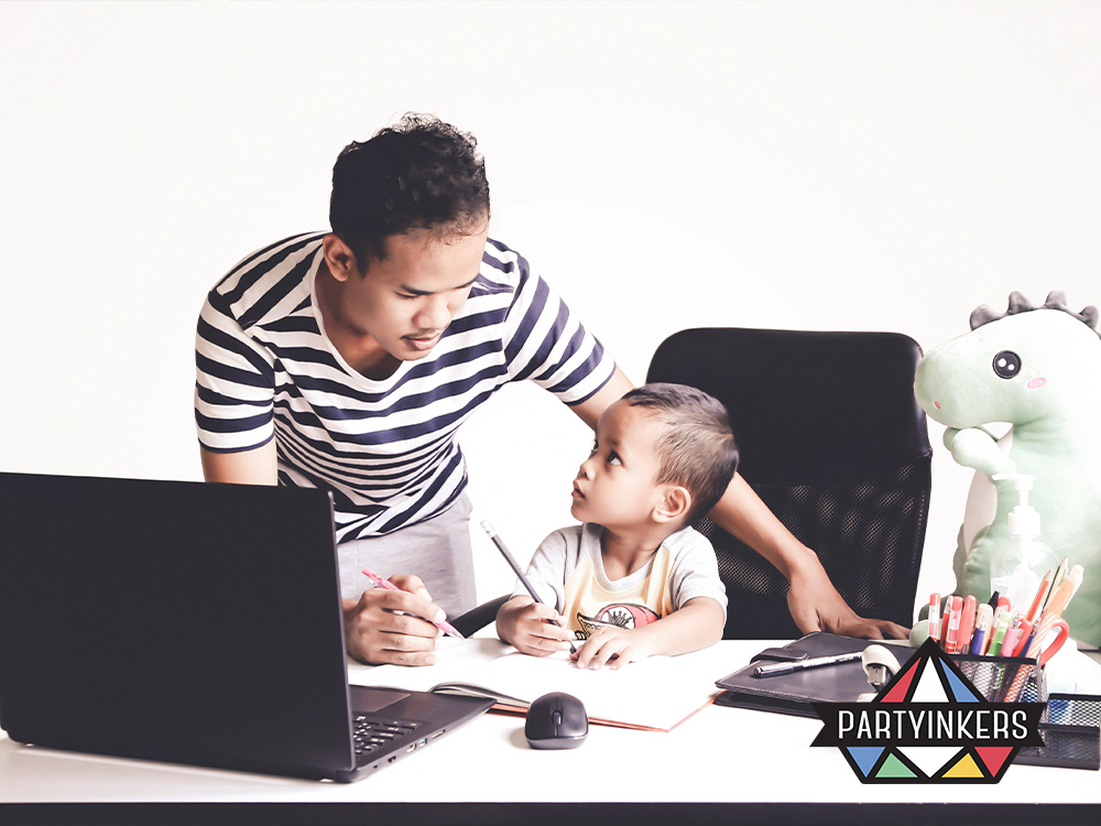 A father working at a desk with his young son, engaging in a task together during a Take Your Child to Work Day event, promoting family involvement in the workplace.