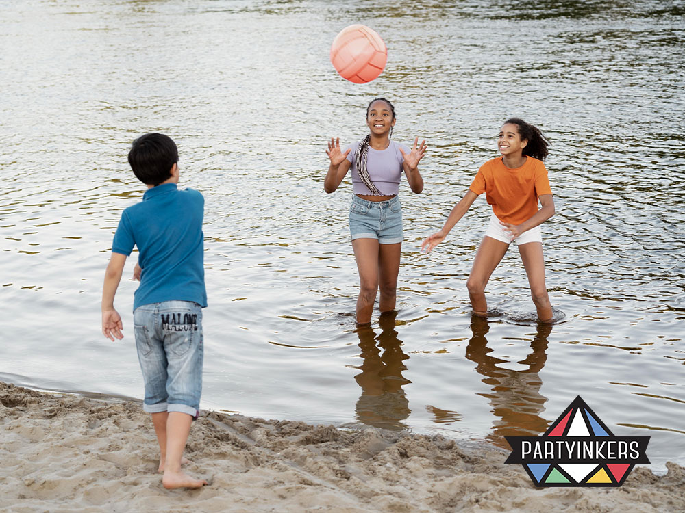 Children playing with a ball in the water at a corporate family day event, enjoying fun water games on a summer day.