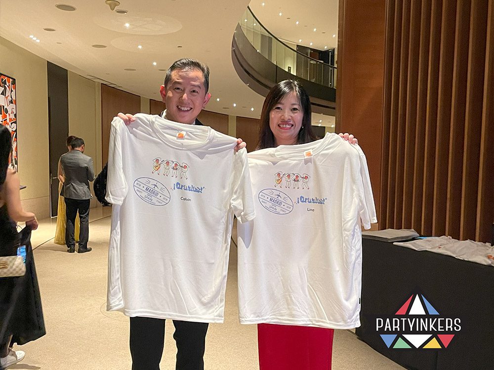 Two attendees proudly showcasing personalized t-shirts received as event giveaways. High-impact giveaways like custom-designed t-shirts boost event participation and provide attendees with unique, memorable keepsakes.