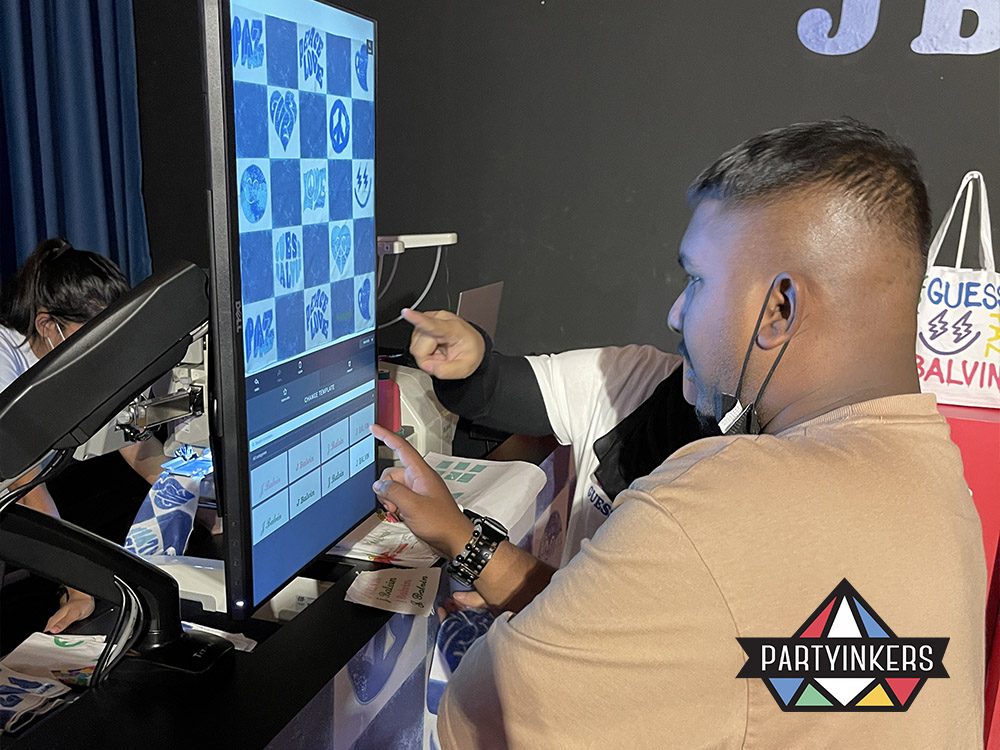 Attendees using a large touchscreen at a Partyinkers booth to design personalized products in real time. This interactive technology enhances event engagement by allowing participants to create custom items and view their designs instantly, providing a memorable and engaging experience.