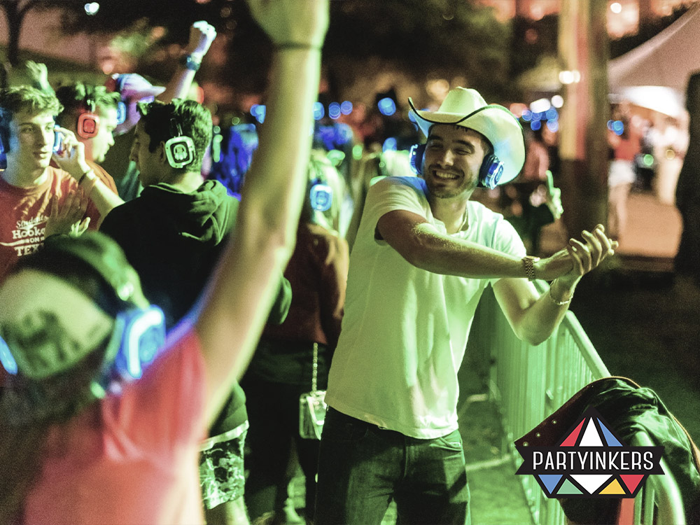 Attendees enjoying a silent disco experience with wireless headphones at an outdoor event, showcasing one of the interactive event ideas where music choices and a unique atmosphere create an engaging and immersive experience for participants.
