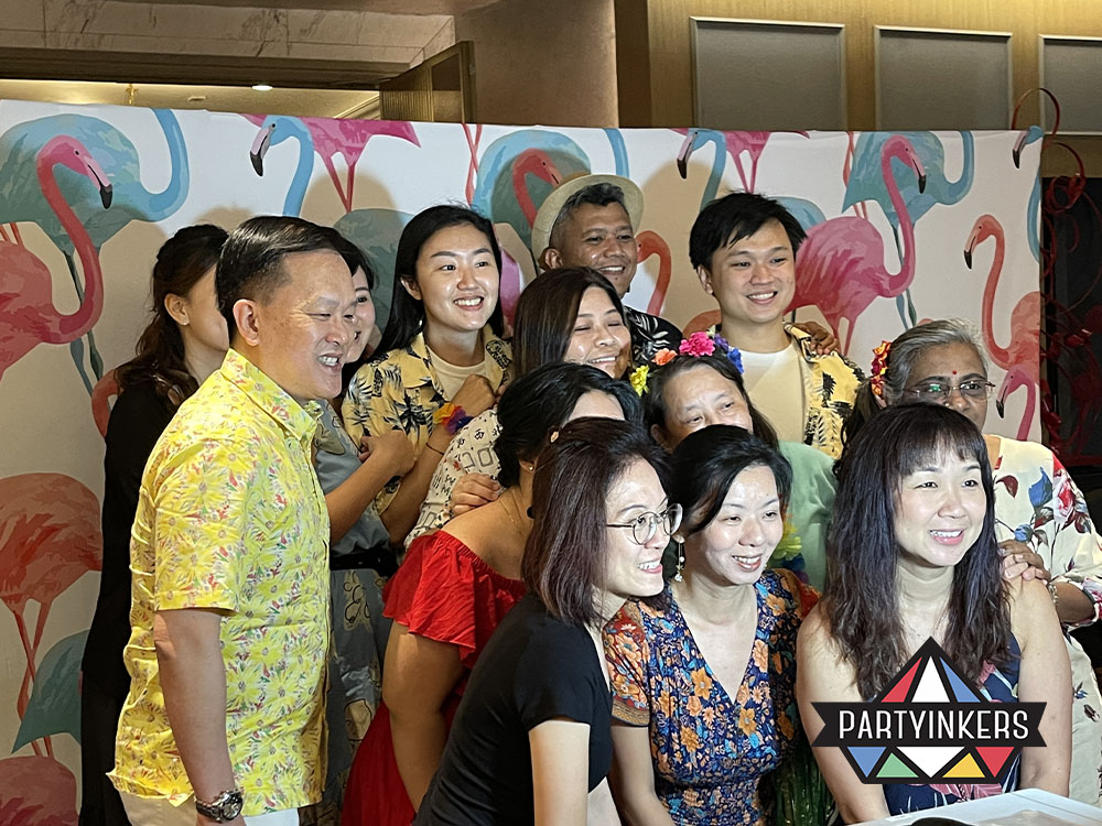 Group of attendees posing for a photo in front of a colorful flamingo-themed backdrop at an event, showcasing one of the many interactive event ideas that encourages engagement and participation.