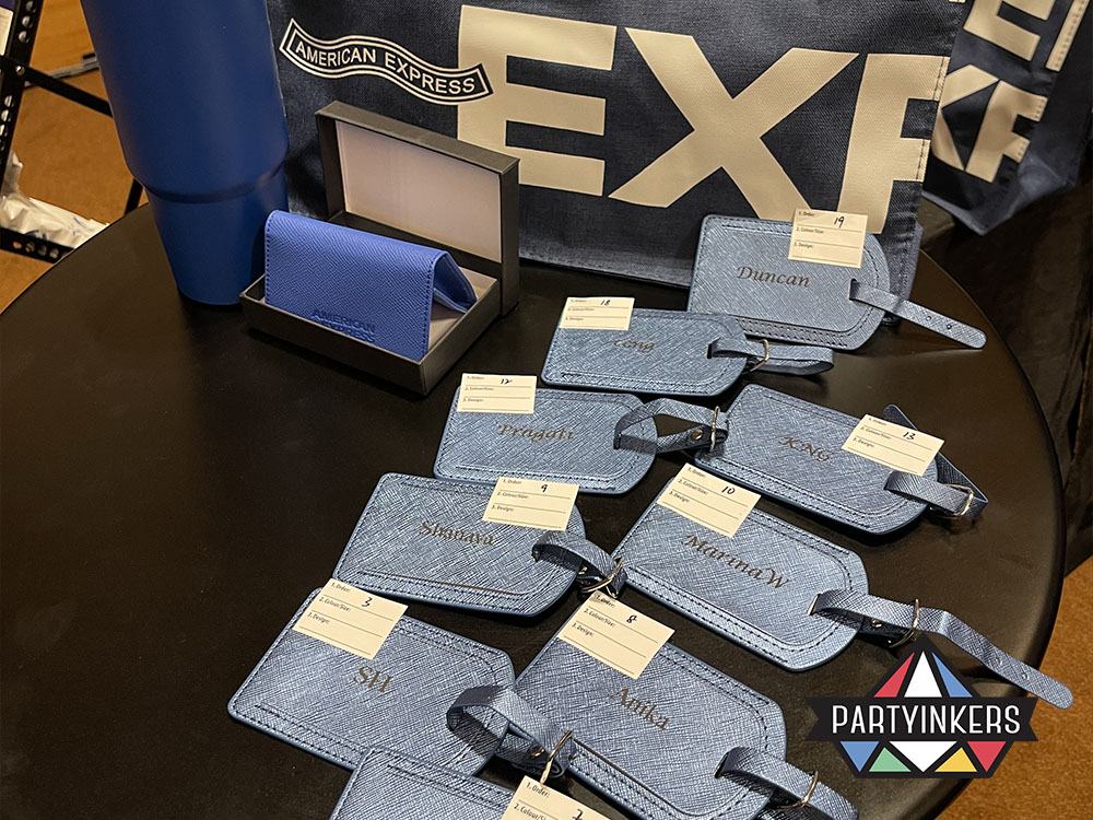 Personalized gifts for a "Corporate Elegance" Dinner and Dance theme, featuring branded leather luggage tags, a cardholder, and a tumbler with the American Express logo, adding a touch of sophistication to the event.