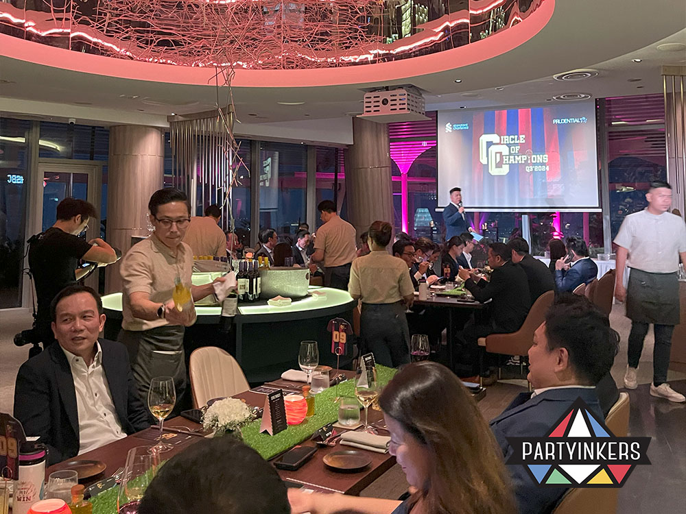 Guests enjoying a sophisticated Dinner and Dance theme event in a modern venue, featuring elegant table settings, vibrant lighting, and an engaging host.