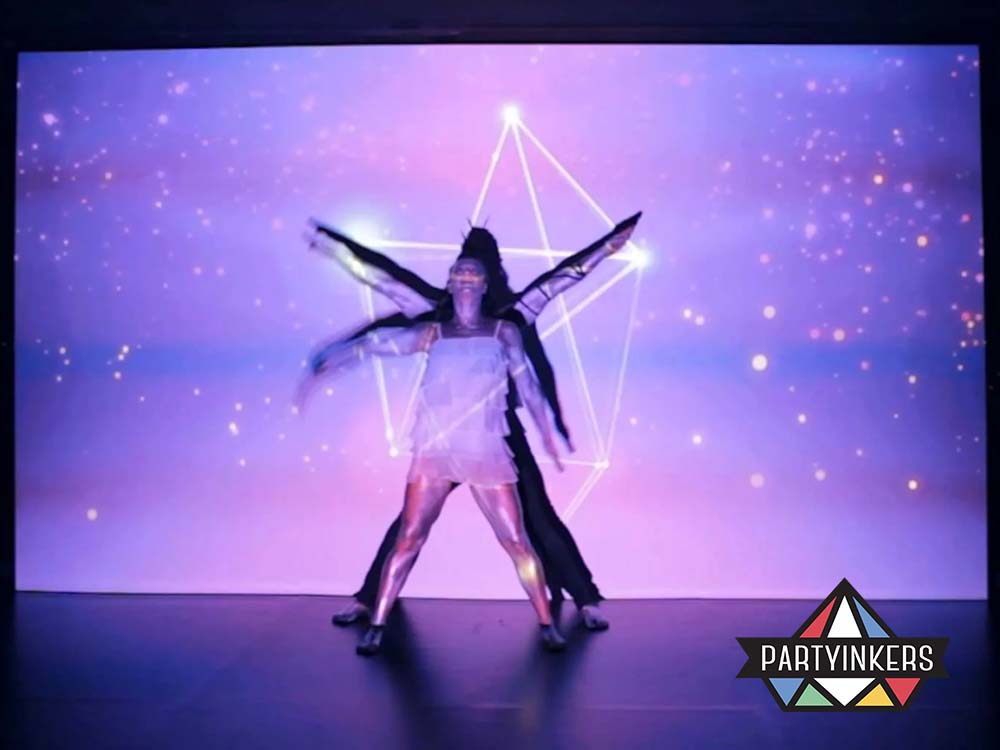 A mesmerizing dance performance featuring a dancer silhouetted against a vibrant, interactive digital projection with geometric shapes and starry effects.