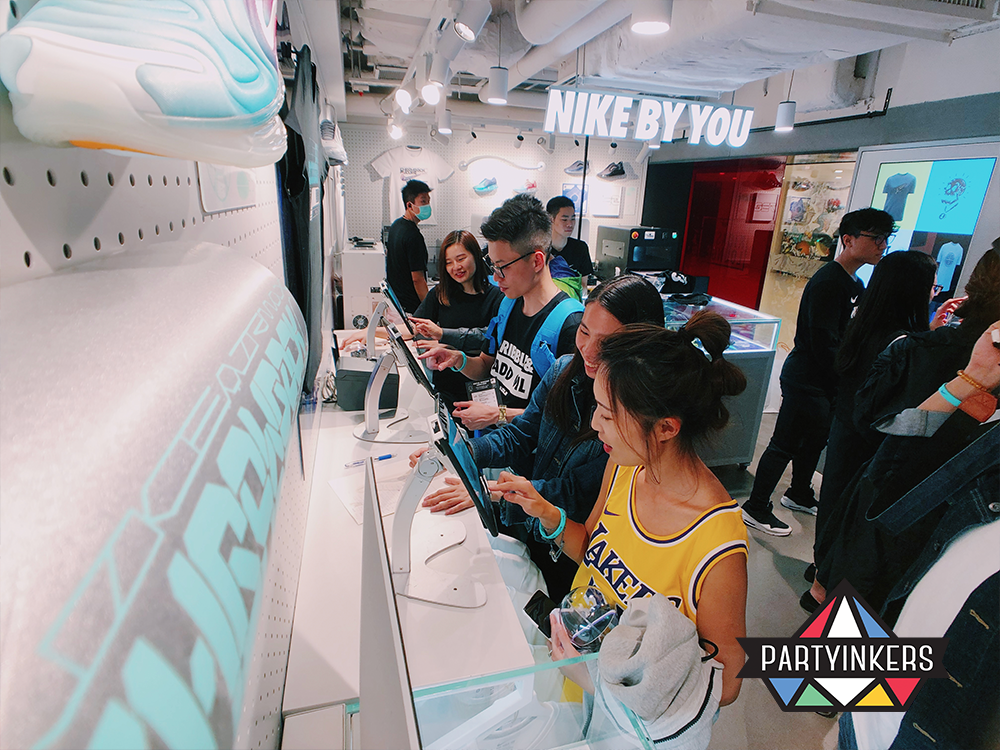 Attendees at the Nike 'By You' event interact with customization stations, creating personalized designs in a vibrant and engaging retail experience.