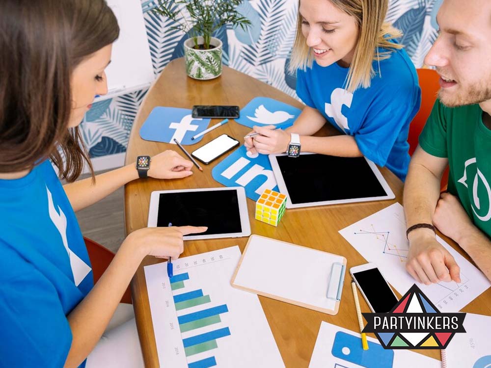 A group of young professionals collaborating at a table, surrounded by digital devices, social media icons, and analytics charts, symbolizing teamwork in social media strategy.