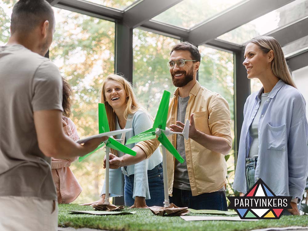 A group of professionals enthusiastically discussing sustainable energy solutions around a table with miniature wind turbine models in a bright, natural-lit space.