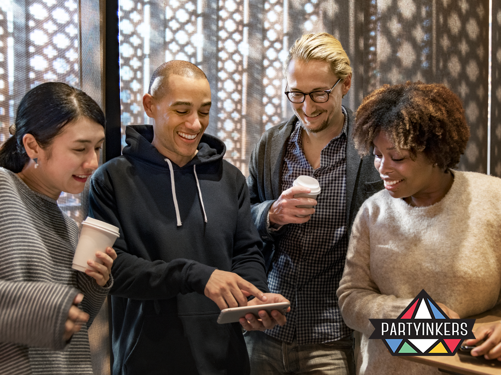 Attendees of a user group event enjoy a collaborative moment, interacting with digital content on a tablet during a networking break. The diverse group, representing various backgrounds and professions, is engrossed in a lively discussion, reflecting the dynamic exchange of ideas typical at such gatherings.
