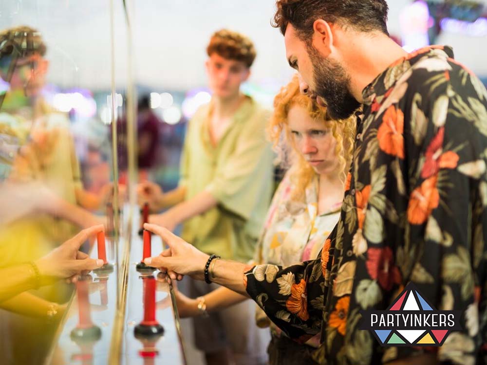 Attendees engaging in a hands-on interactive game at an event, focusing intently as they press buttons on a mirrored console.