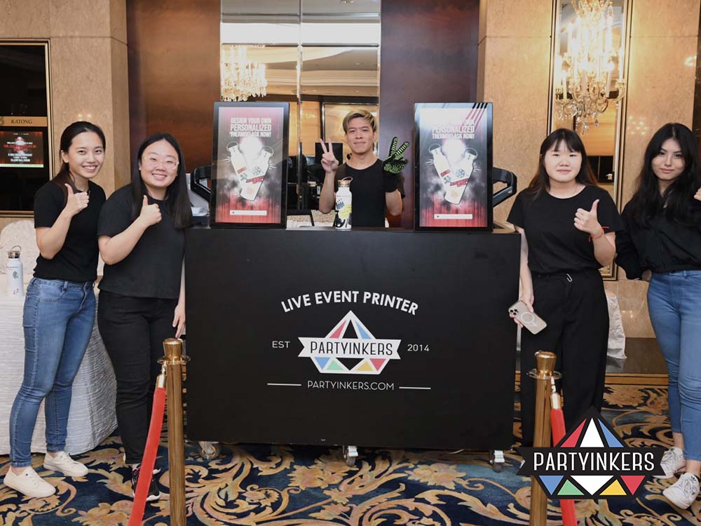 The Partyinkers live event team smiling at their booth, ready to assist guests with creating personalized merchandise.