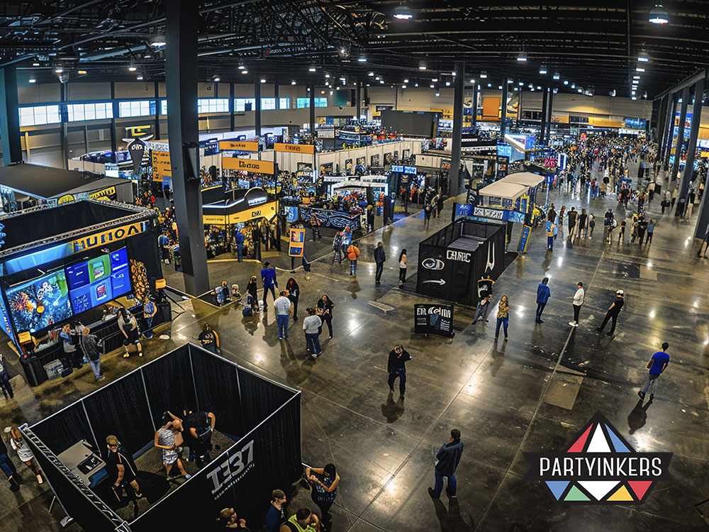 Wide-angle view of a bustling trade show with multiple booths and attendees, showcasing the dynamic energy of the event.
