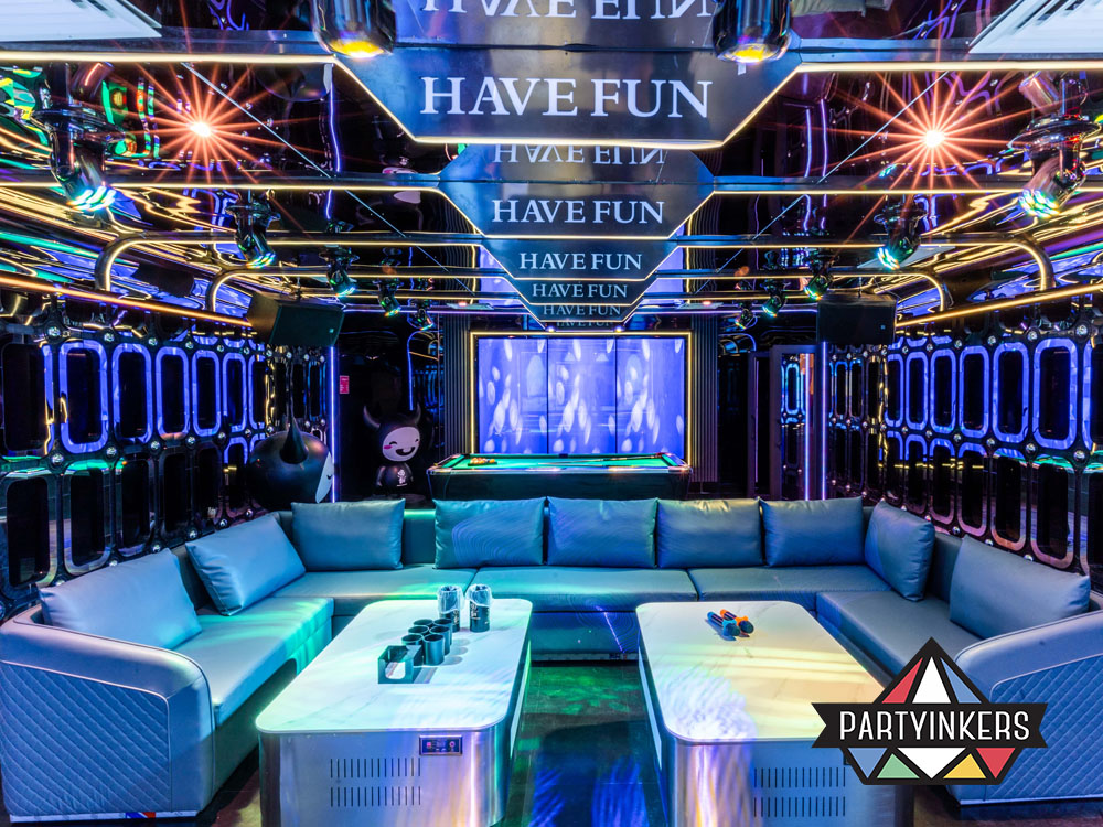 A stylish and vibrant lounge space with a futuristic design, featuring comfortable seating, neon lighting, and a cozy bar atmosphere.