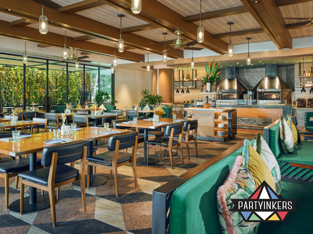 A cozy restaurant with wooden furniture and vibrant greenery, featuring a spacious dining area and a modern open kitchen concept.