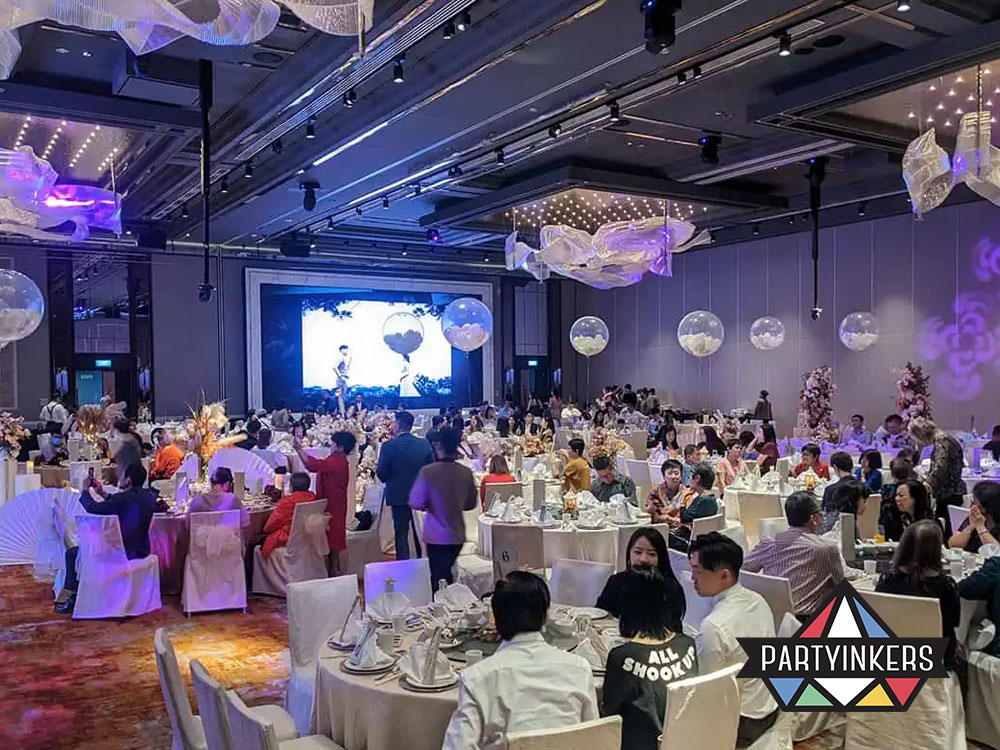 An elegant ballroom set for a gala dinner, featuring lavish table setups, mood lighting, and a large stage with a backdrop screen.