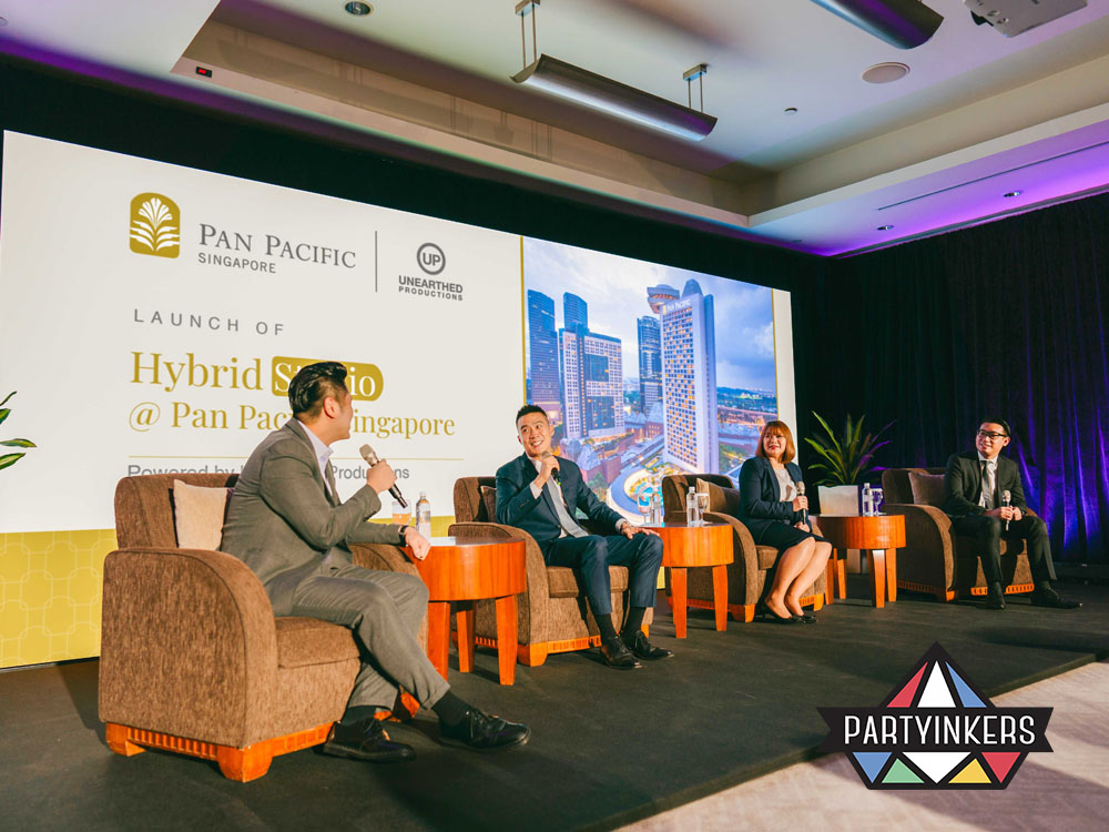 A professional panel discussion at Pan Pacific Singapore during the launch of the Hybrid Studio, featuring speakers seated on a well-lit stage with a city skyline backdrop.
