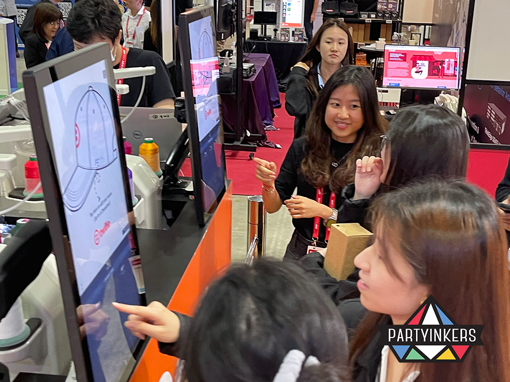 Attendees interacting with Partyinkers' live customization booth, designing personalized conference merchandise for a memorable experience.
