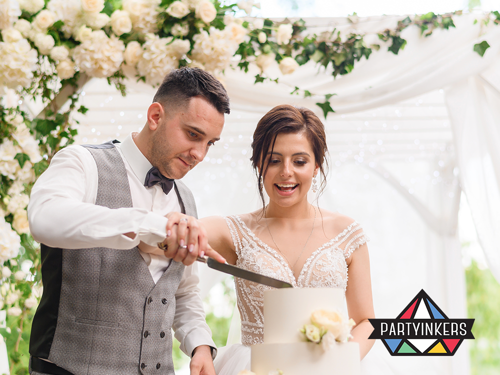 "A bride and groom cutting their wedding cake together, surrounded by elegant floral decorations, symbolizing joy and celebration."