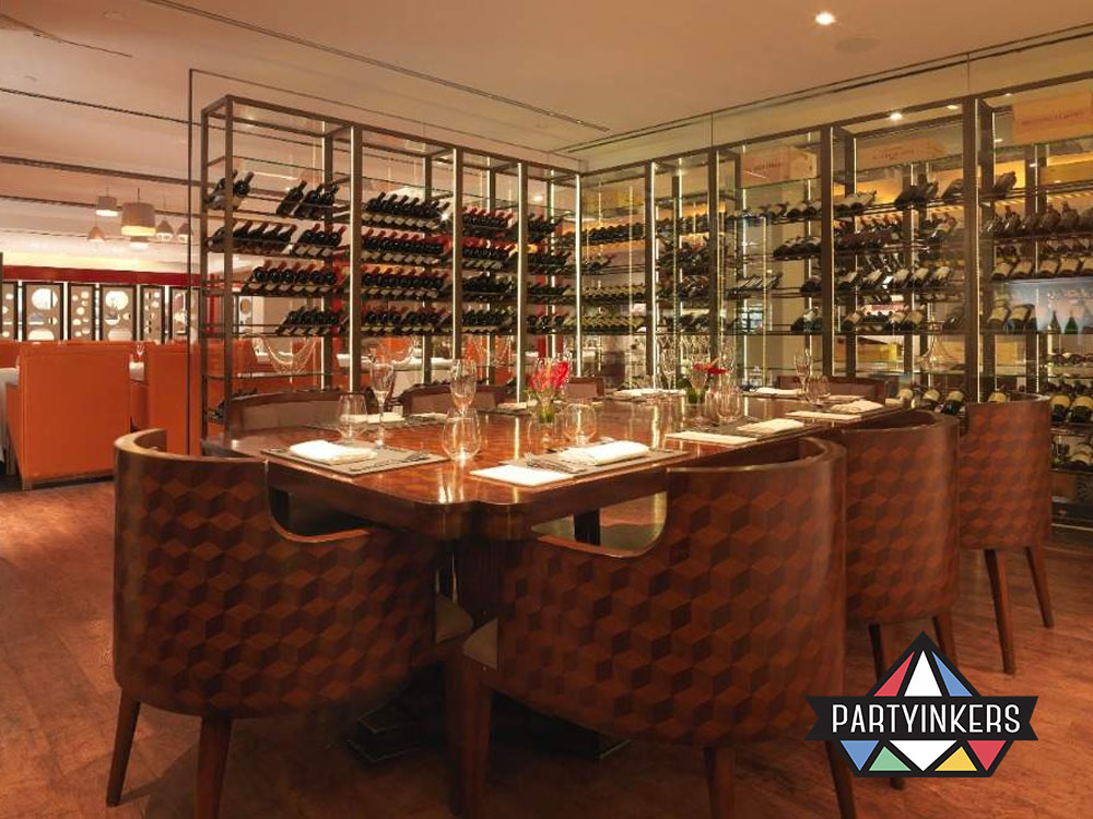A sophisticated dining space with a luxurious wooden table surrounded by elegant chairs, set amidst a backdrop of floor-to-ceiling wine racks.