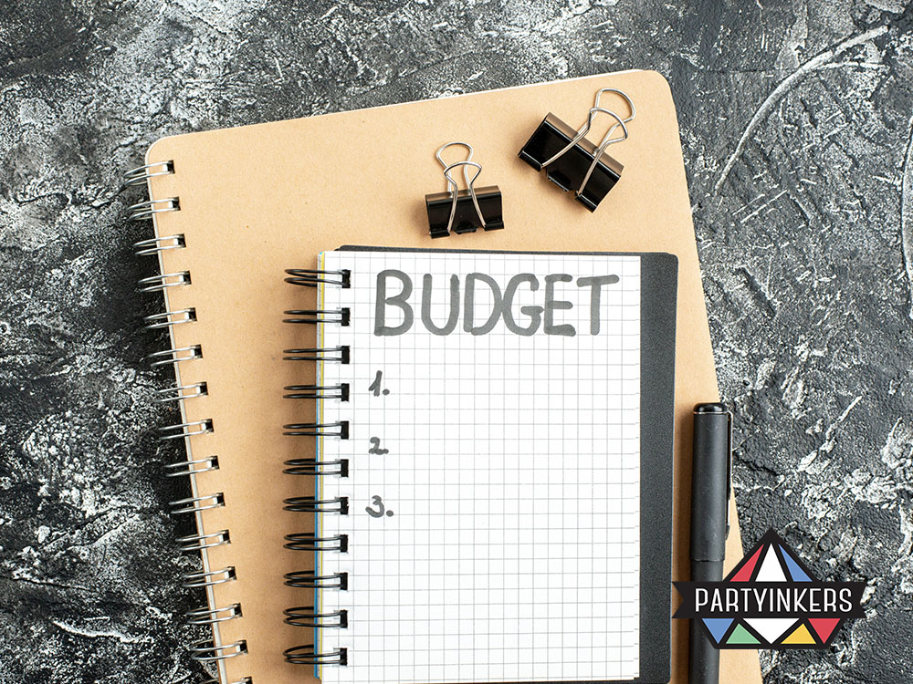 A neatly arranged notebook with "Budget" written on it, paired with clips and a pen, signifying event budget planning.