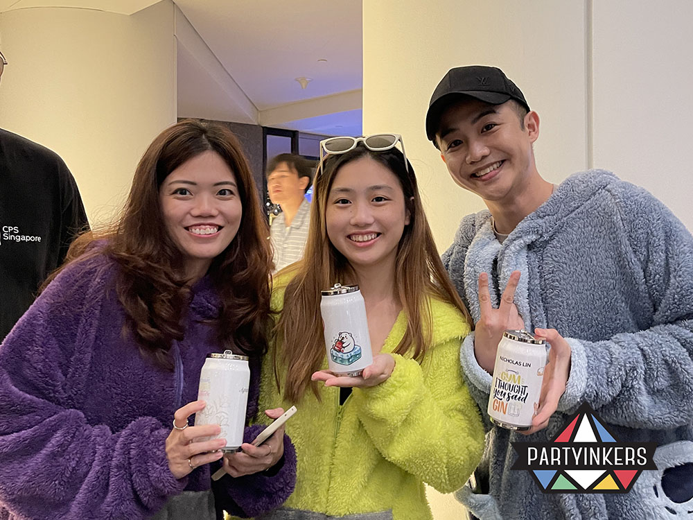Three happy attendees holding personalized drink cans printed live at the Partyinkers booth during a corporate dinner and dance event.