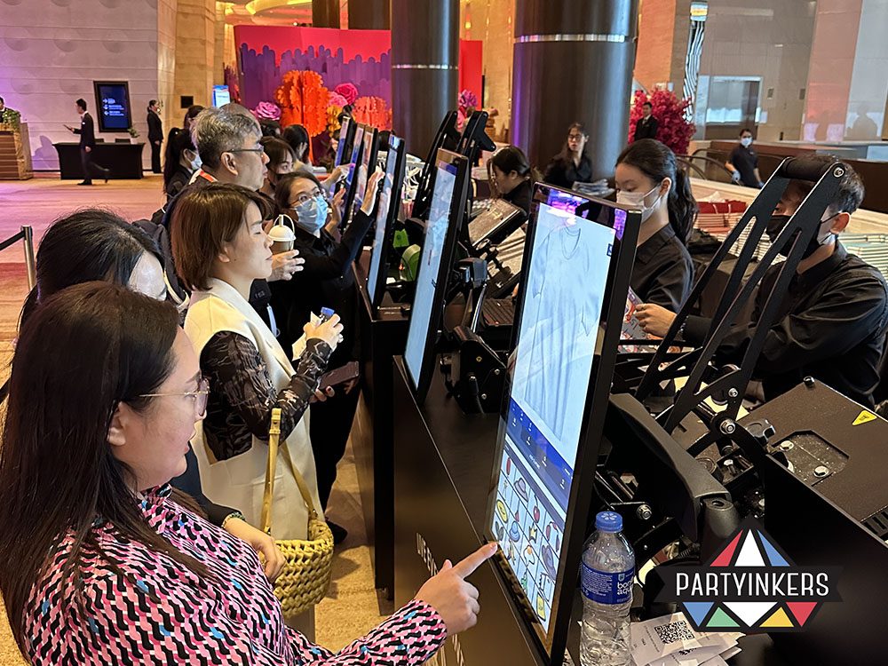 Event attendees engaging with a live printing station, customizing their designs on interactive touchscreens.