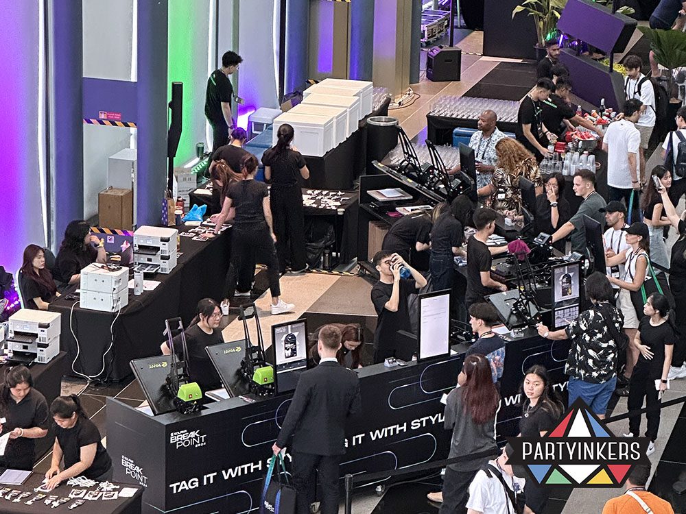 A bustling event showcasing a large-scale customization booth with multiple stations and attendees interacting with the setup.