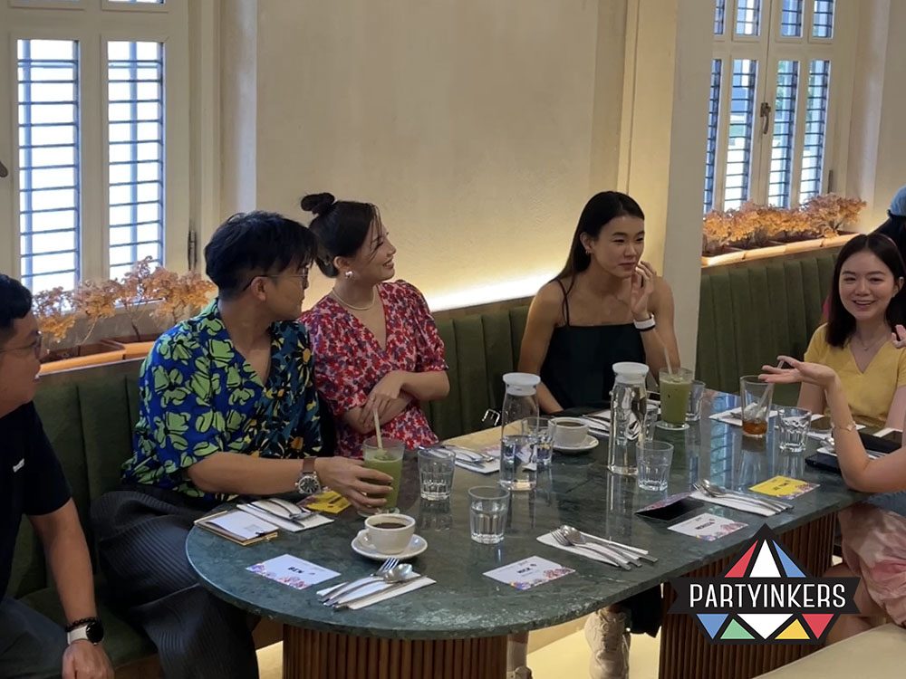 A group of friends enjoying a casual meal and conversation at a restaurant with elegant interiors and soft lighting.