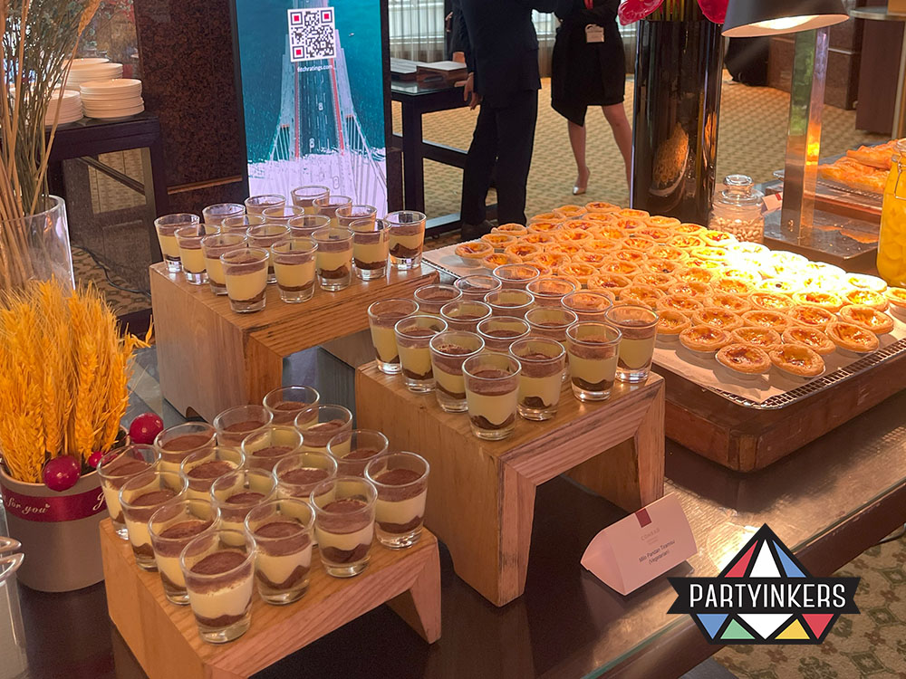 A beautifully arranged dessert station featuring tiramisu and egg tarts at a corporate dining event.