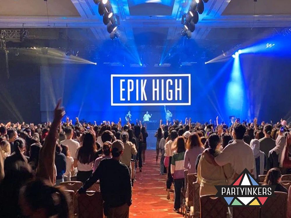 A dynamic concert by Epik High with a large crowd enjoying the live performance under vibrant blue stage lighting.