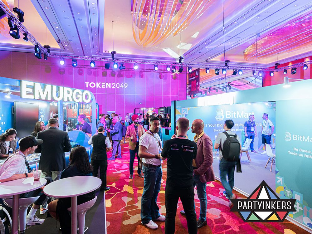 A bustling exhibition floor at TOKEN2049, showcasing vibrant booths, attendees networking, and a colorful, tech-inspired ambiance.