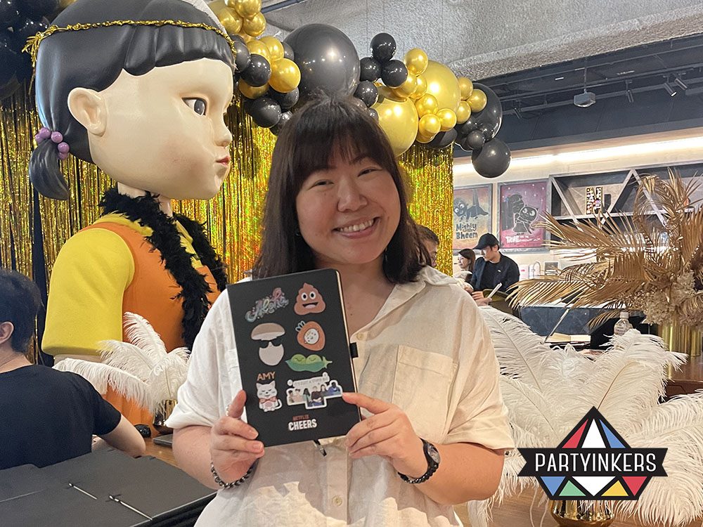A smiling attendee holding a customized notebook decorated with vibrant stickers at a Netflix-themed event booth.