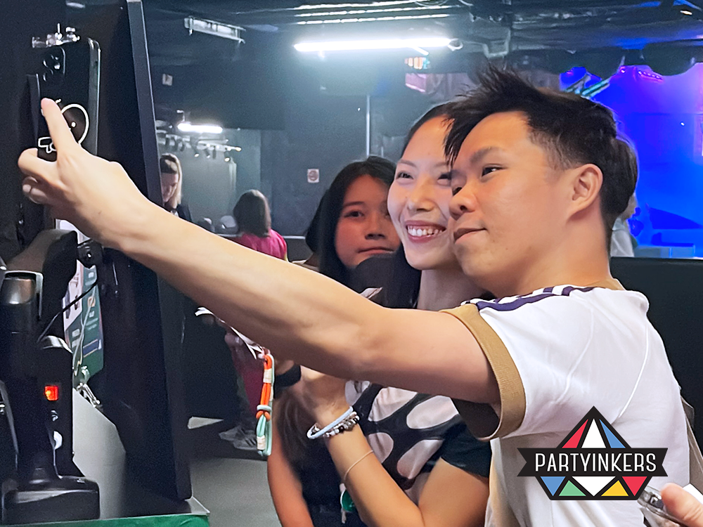 "Two attendees interacting with a photo kiosk, taking a selfie and engaging with the interactive event booth by Partyinkers, fostering a fun and memorable experience.