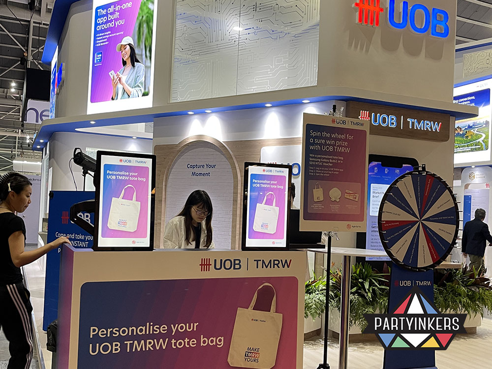 A customized tote bag station at a UOB event, featuring a digital spin-the-wheel activity for prizes and interactive tote personalization.