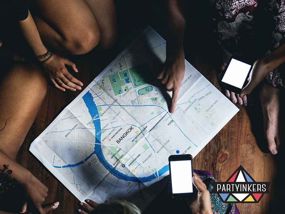 People gathered around a city map of Bangkok, planning their journey with smartphones and sharing ideas