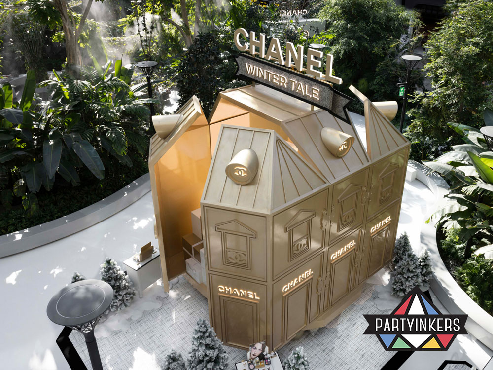 A luxury brand activation idea by Chanel, featuring an immersive winter-themed pop-up store. The elegant golden structure, set in a lush environment, invites visitors to experience the brand’s exclusive collection through interactive storytelling