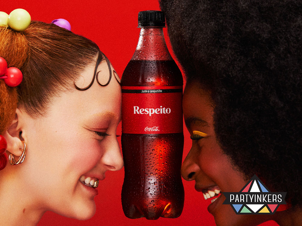  Two women smiling with a Coca-Cola bottle between them, emphasizing a unique brand activation idea that promotes inclusivity, connection, and brand identity through creative marketing.