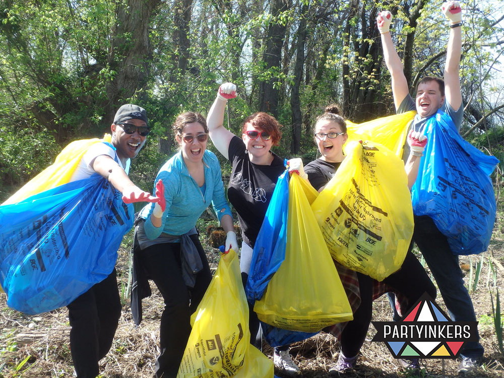 A group of enthusiastic volunteers participating in a sustainability-driven brand activation idea, collecting waste in blue and yellow bags while celebrating their efforts outdoors.