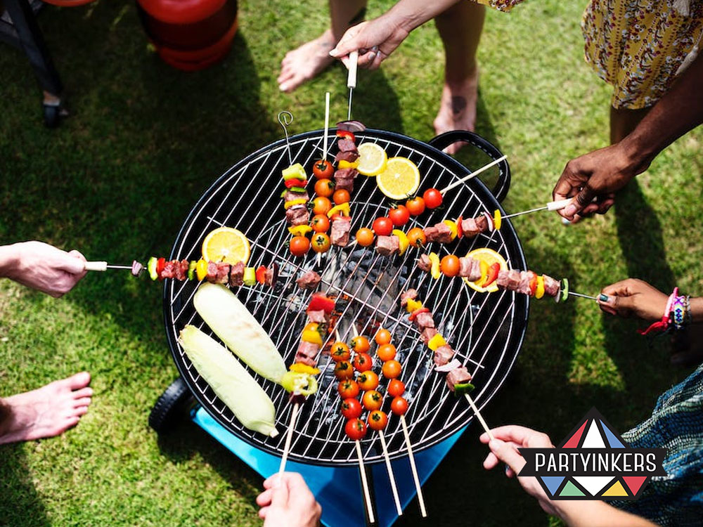 Employees grilling skewers together during a company barbecue at an outdoor corporate event.